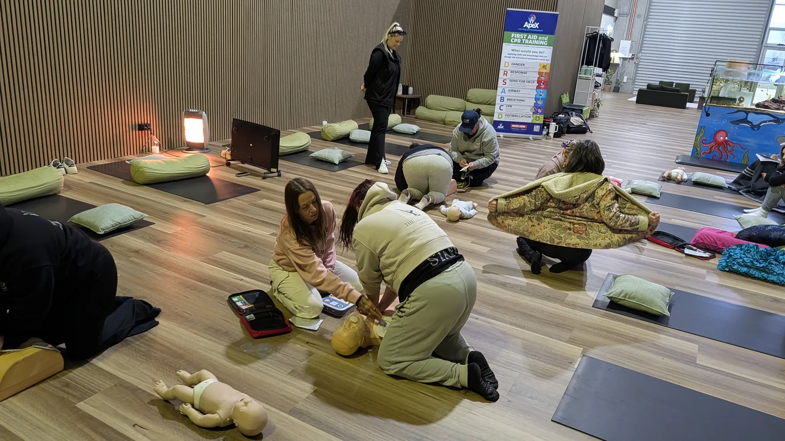 Participants practising adult CPR compressions on manikins at an Apex first aid session